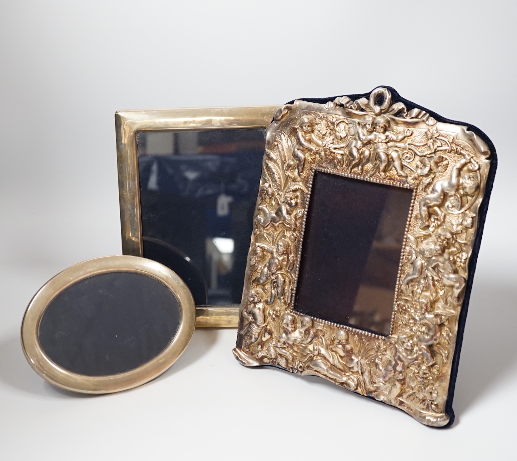 Three assorted modern silver mounted photograph frames, the largest decorated with putti amongst flowers, 27.5cm.